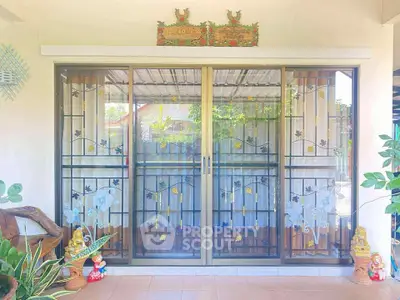 Charming home entrance with decorative sliding glass doors and vibrant garden accents.