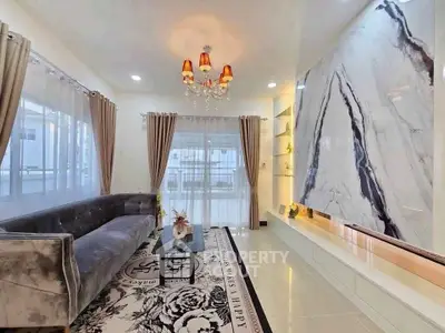 Luxurious living room with elegant chandelier and marble accent wall, perfect for sophisticated gatherings.