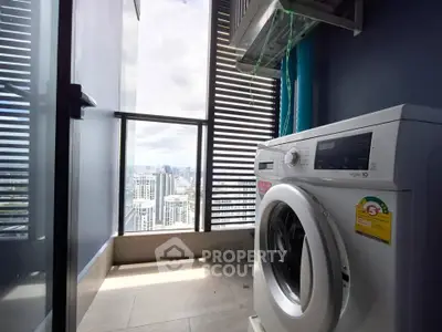 Modern high-rise apartment with city view and washing machine on balcony.