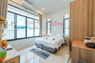 Charming bedroom with modern decor, large windows, and cozy ambiance perfect for relaxation.