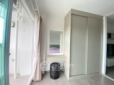 Modern bedroom with sleek wardrobe and balcony access, featuring minimalist design and natural light.