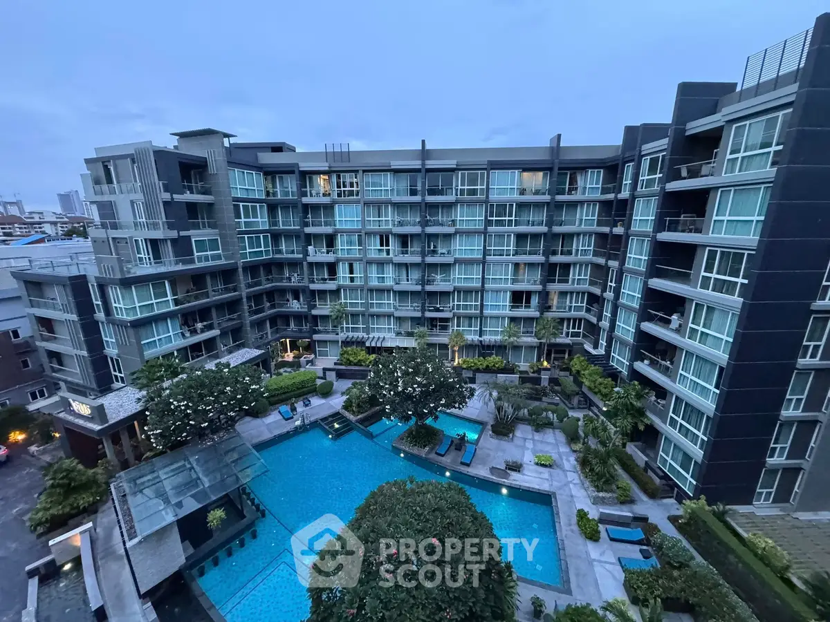 Luxurious modern apartment complex with stunning pool and lush garden view.
