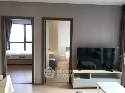 Modern apartment interior with spacious living room and two bedrooms, featuring sleek furniture and natural light.