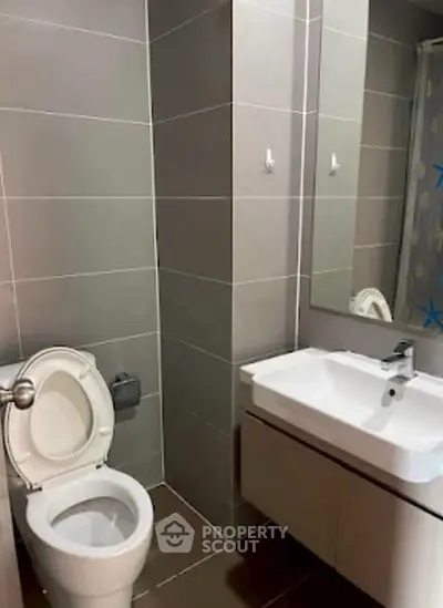 Modern bathroom with sleek fixtures and neutral tiles, featuring a stylish vanity and toilet.