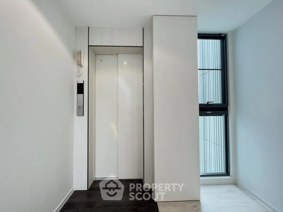 Modern elevator entrance in a sleek residential building with natural light.