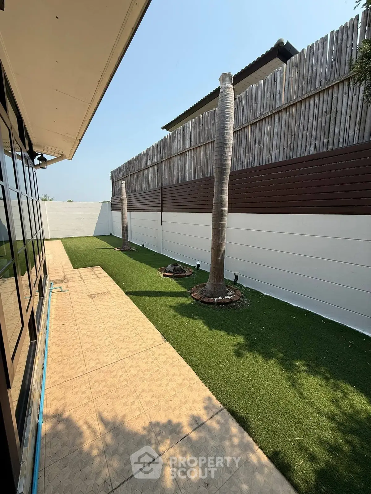 Charming garden area with artificial grass and palm trees, perfect for outdoor relaxation and entertainment.