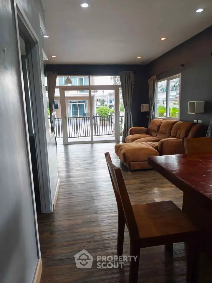 Spacious living room with modern decor and large windows opening to a balcony view.
