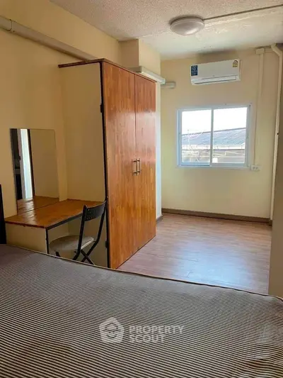 Cozy bedroom with wooden wardrobe, desk, and window view