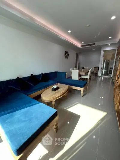Spacious living room with modern blue sectional sofa and elegant dining area, perfect for entertaining.