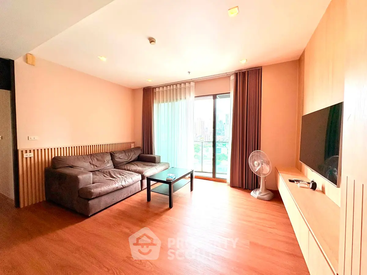 Spacious living room with modern decor and city view, featuring a cozy sofa and entertainment setup.