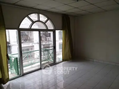 Spacious room with large window and balcony access in urban apartment.