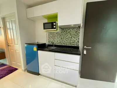 Modern compact kitchen with sleek cabinetry and mosaic backsplash in a stylish apartment.
