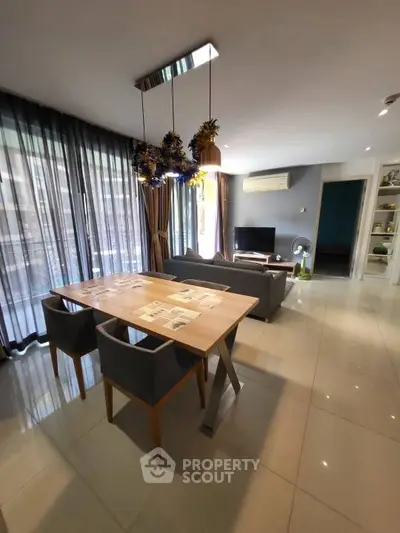 Modern living room with elegant dining area and large windows for natural light.