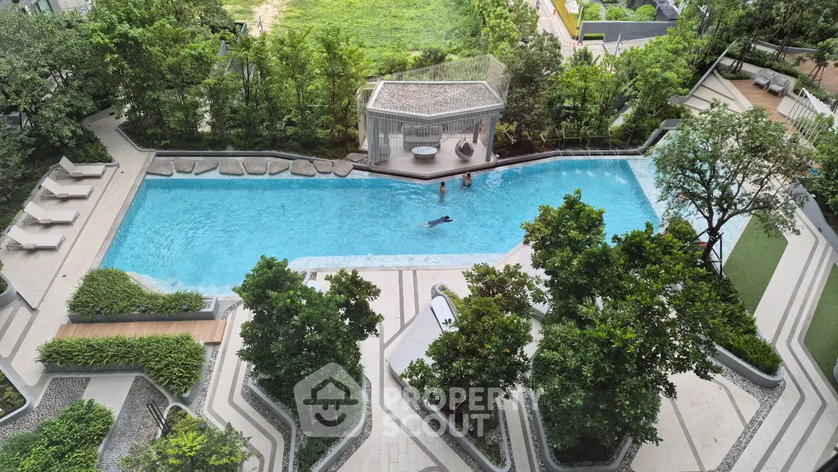 Luxurious outdoor pool surrounded by lush greenery in a modern residential complex.