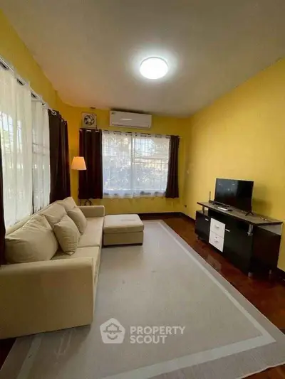 Cozy living room with yellow walls, modern sofa, and TV setup