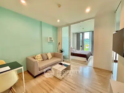 Modern open-plan living room with cozy seating and bedroom view, featuring stylish decor and natural light.