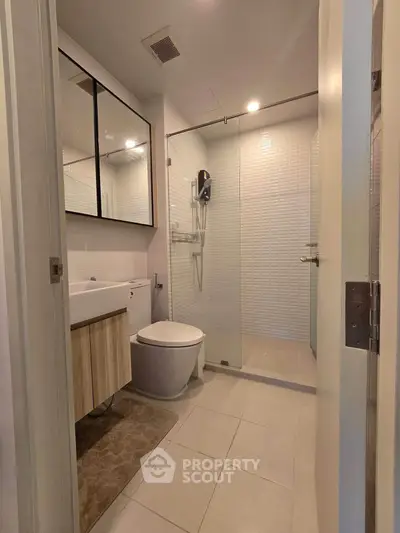 Modern bathroom with glass shower and sleek fixtures in contemporary apartment.