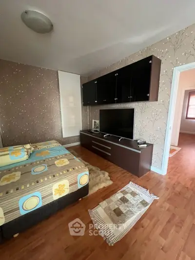 Cozy bedroom with modern TV unit and stylish wallpaper, perfect for relaxation and entertainment.
