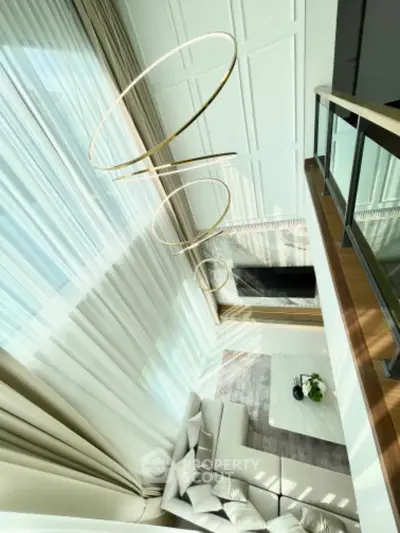Luxurious high-ceiling living room with modern chandelier and elegant decor