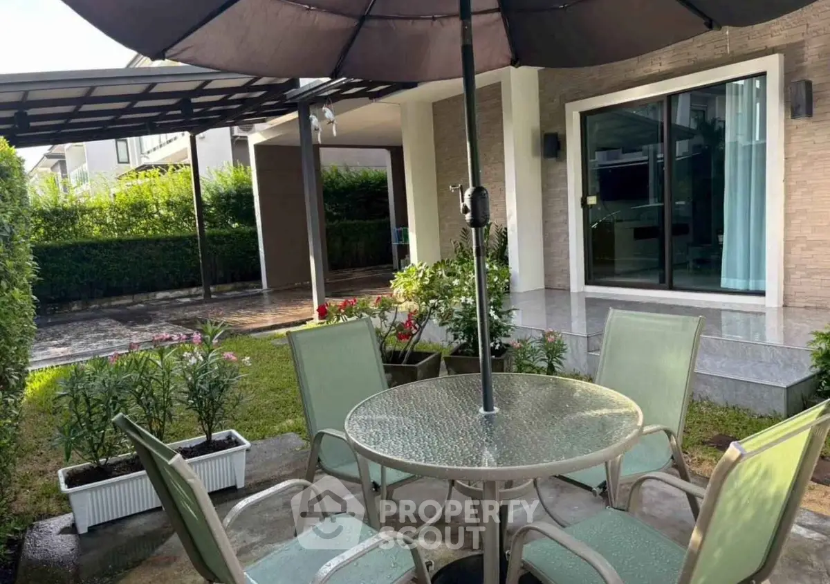 Charming garden patio with glass table and umbrella, perfect for outdoor relaxation.