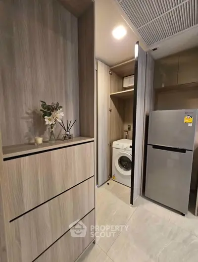 Modern kitchen with sleek cabinetry, washing machine, and fridge in compact layout.
