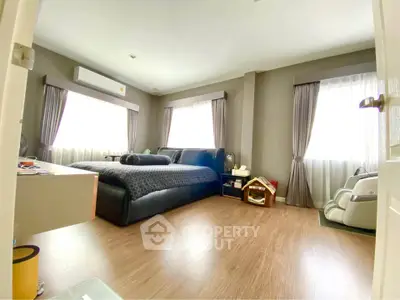 Spacious bedroom with modern decor and large windows for natural light.