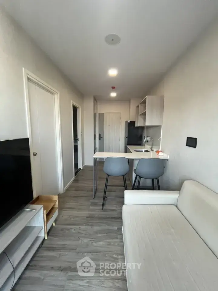 Modern apartment interior with sleek kitchen and cozy living area, featuring contemporary furnishings and neutral tones.