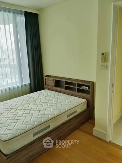 Cozy bedroom with large window and wooden flooring, featuring a comfortable bed and modern design.