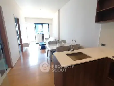 Modern open-plan kitchen and dining area with sleek wooden flooring and natural light.