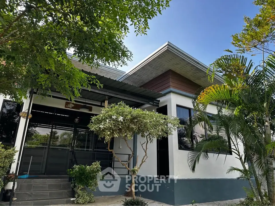 Modern single-story house with lush greenery and sleek architectural design.