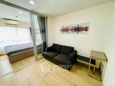 Modern apartment with cozy living room and bedroom separated by glass sliding doors, featuring wooden flooring.