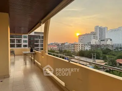 Spacious balcony with stunning city view at sunset, perfect for relaxation.
