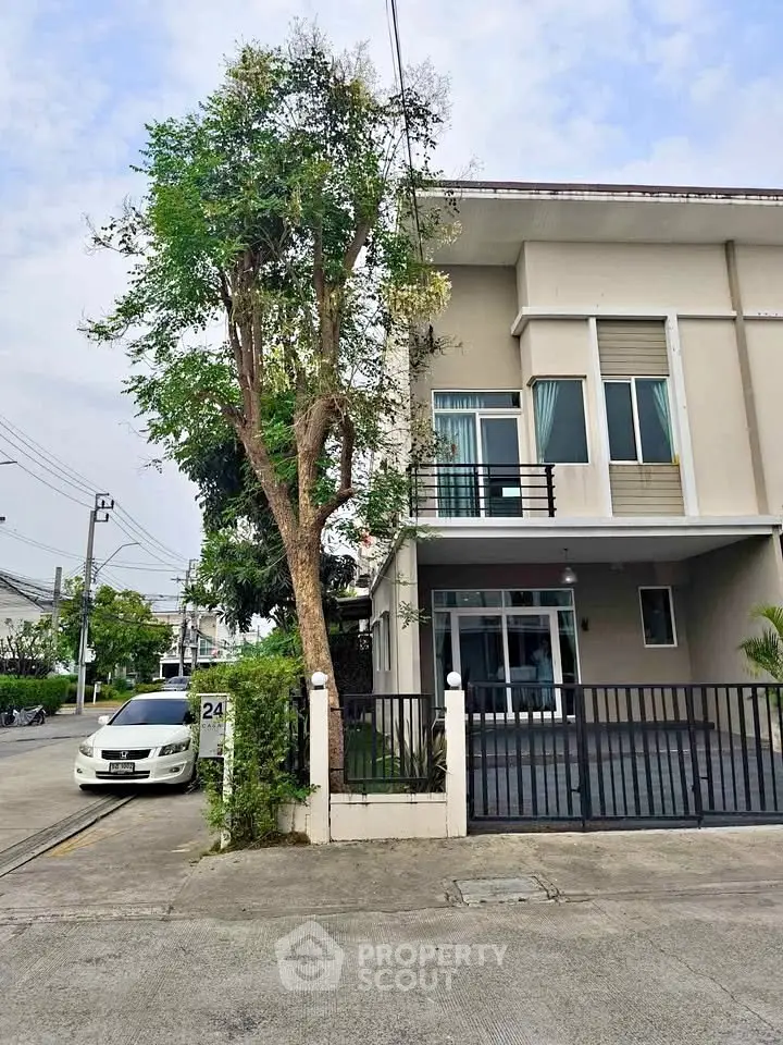 Modern two-story townhouse with balcony and gated driveway in suburban neighborhood.