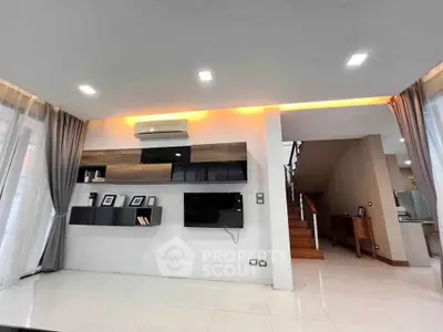 Modern living room with sleek design and built-in shelving, featuring a wall-mounted TV and stylish lighting.