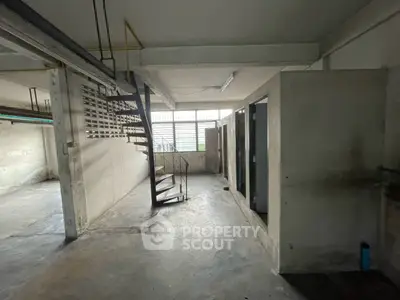 Spacious industrial-style basement with concrete floors and spiral staircase