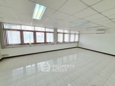 Spacious empty room with large windows and tiled flooring, perfect for office or living space.
