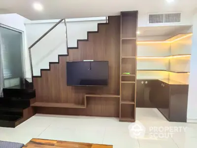 Modern living room with stylish staircase and built-in TV unit