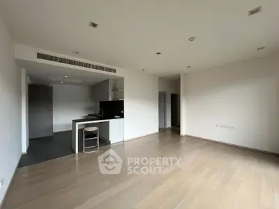 Spacious open-plan living area with sleek hardwood floors and a modern kitchen featuring a built-in oven and ample cabinetry, perfect for entertaining.