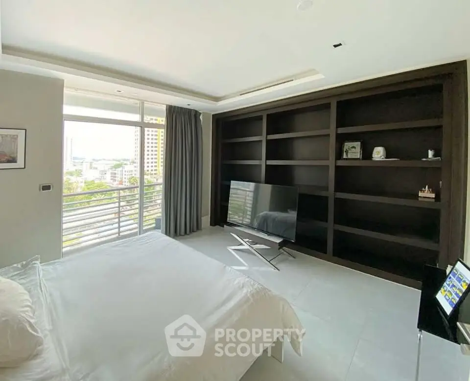 Spacious bedroom with modern decor and large window offering city views.