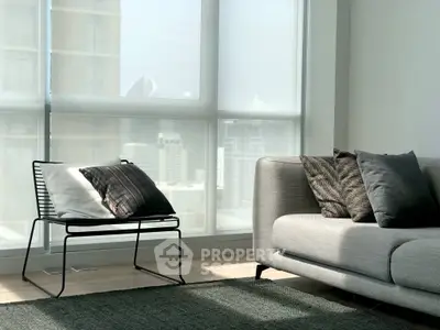 Modern living room with stylish furniture and large windows offering city views.