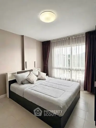 Spacious bedroom with modern decor and large window offering natural light.