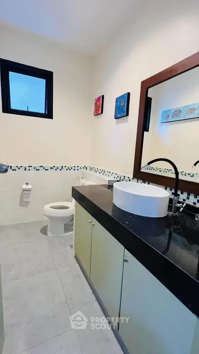 Modern bathroom with sleek black countertop and stylish sink in a contemporary home.