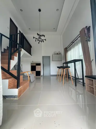 Modern living room with high ceiling and stylish staircase in a contemporary home.