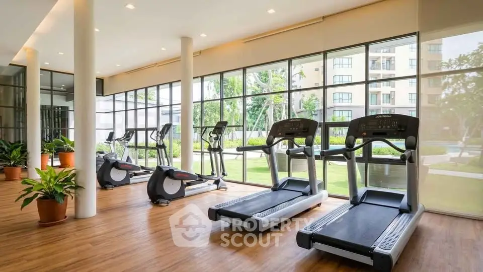 Modern gym with large windows and treadmills in a luxury apartment complex.