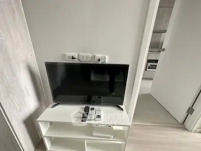 Modern apartment interior with TV and open kitchen layout, showcasing sleek design and functionality.