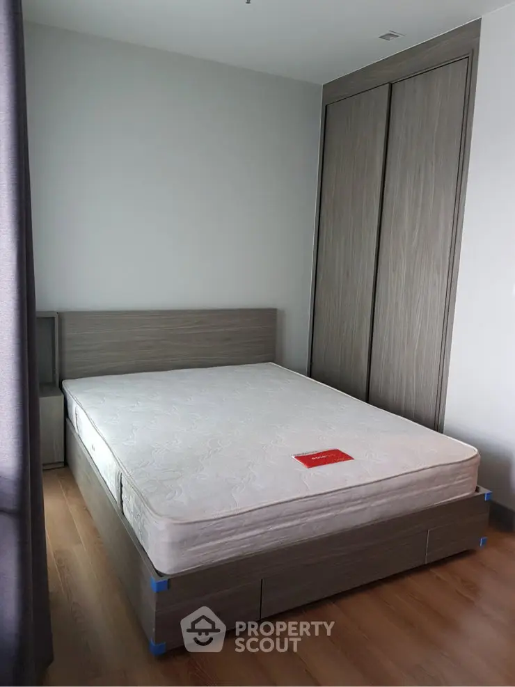 Modern bedroom with wooden flooring and built-in wardrobe, featuring a minimalist design and natural light.