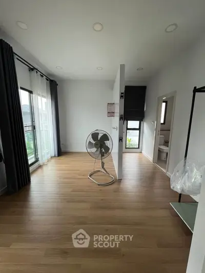 Spacious room with wooden flooring and large windows for natural light