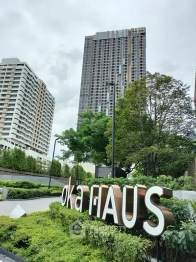 Modern high-rise building with lush landscaping and prominent signage in urban setting.