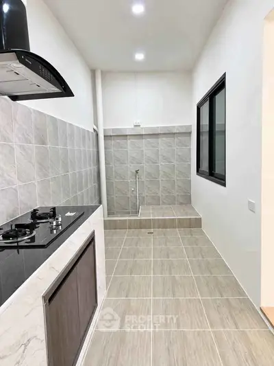 Modern kitchen with sleek gas stove and tiled backsplash in a minimalist design.