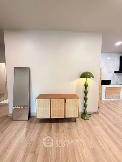 Stylish modern living room with wooden flooring, chic cabinet, and unique green lamp.